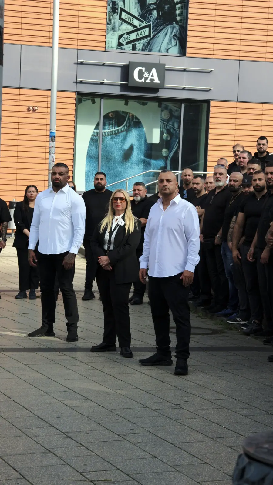 Die Geschäftsleitung in Weiß vor dem Team in Schwarz